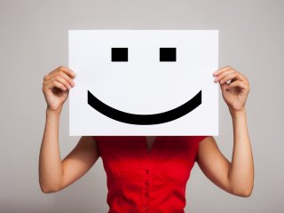 Female holding smiley face sign up